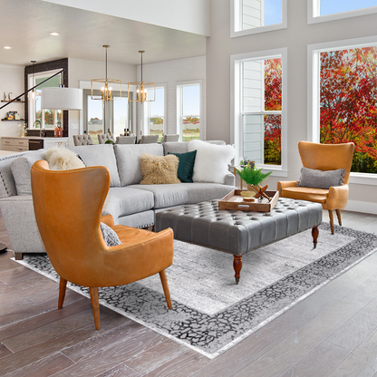Modern living room with beautiful staging in autumn using Grey Mandala Area Rug, grey couch, orange armchairs and large leather coffee table