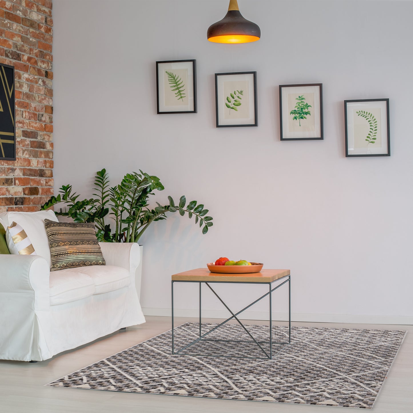 Living room with brick wall, plants, white armchair, small coffee table on geometric patterned Smyrna Beige Rug 