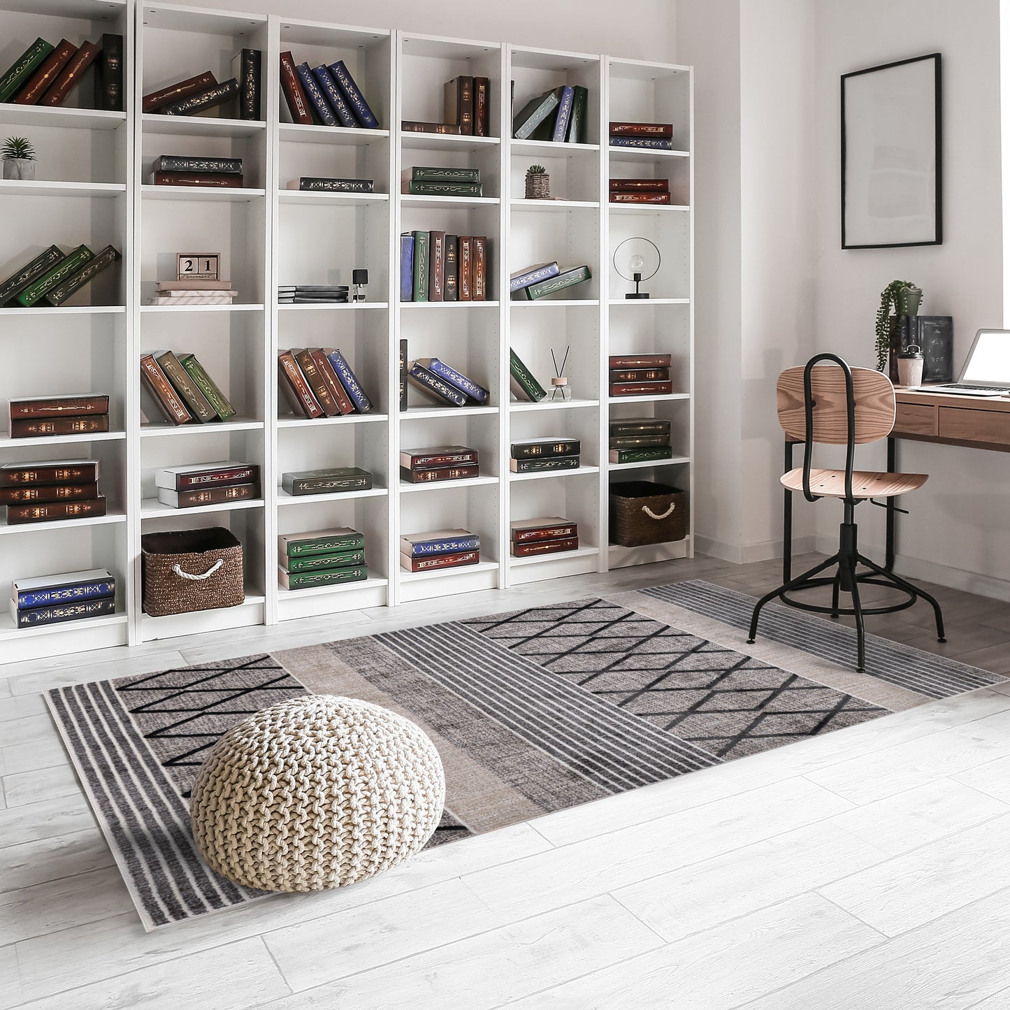 Modern home office with wall-to-wall white shelves, wooden study desk, chair on striped and zigzag design grey area rug