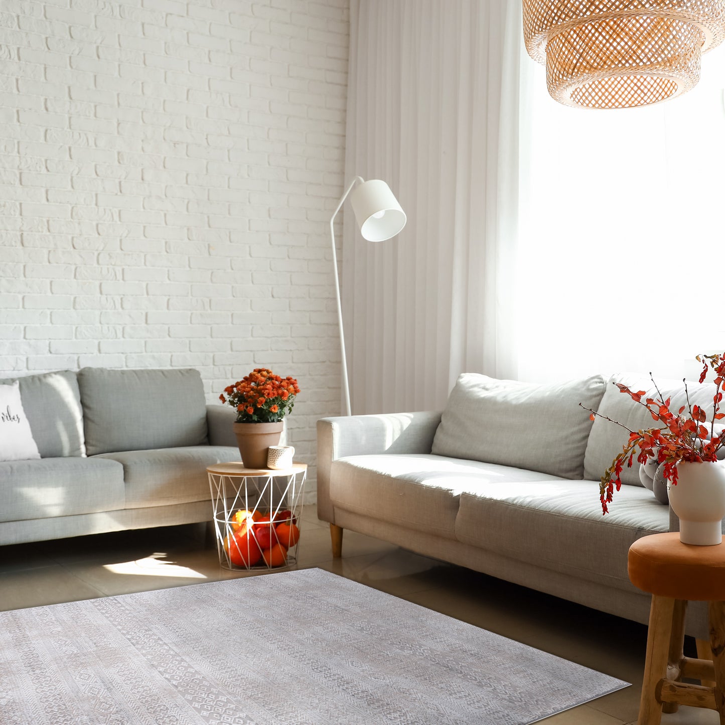 Bright modern family room with grey sofas, white and rattan lamps, warm accents and autumn plants